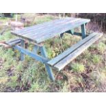 A garden table with integral batton bench seats and slatted table top, raised on angled