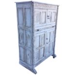 A carved dowel-jointed limed oak cupboard with floral panelled frieze above two doors and a slide,