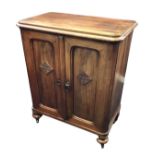 A mahogany collectors cabinet with rectangular rounded top above panelled doors mounted with