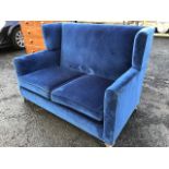 An unusual wing-back sofa with padded frame and sprung seat with loose cushions, raised on square