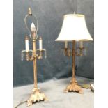 A pair of painted cast iron tablelamps with scrolled leaf moulded triangular bases beneath columns