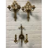 A pair of ormolu wall sconces, each with two scrolled branches framing leaf cast cherub, the wall