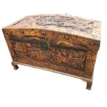 A domed camphorwood eastern chest extensively carved with panels of fighting warriors and figural