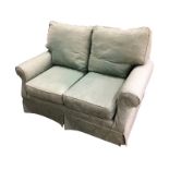 A two seater sofa upholstered in green damask fabric, with loose cushions and covers, raised on