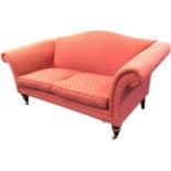 An upholstered camel back sofa with splayed scrolled arms above sprung seat with loose cushions,
