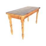 A rectangular pine kitchen table with thick rounded top on plain rails above turned tapering