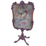 A Victorian mahogany tapestry screen with scroll carved frame enclosing a stumpwork panel of a