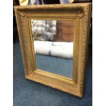 A rectangular gilt framed mirror, the bevelled plate in wide concave ribbed gilt & gesso frame