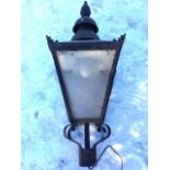 A Victorian style street lantern with round chimney above square tapering enclosure with hinged door