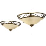 A pair of contemporary hanging lights with acid etched glass bowls in brushed brass scrolled
