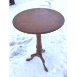 A circular mahogany occasional table raised on turned column with tripartite shaped legs. (18.75in x