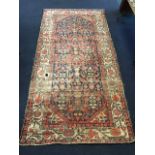 A large antique Indian rug woven with busy blue field of linked floral designs, framed by conforming