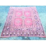 An oriental style rug woven with four panels of lozenge medallions on madder ground within a