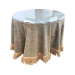 A circular plate glass topped modern table with fringed green brocade type cover. (40in x 30.75in)