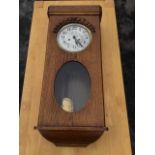 A 1930s oak wallclock, the rectangular rounded case with moulded band above a circular convex