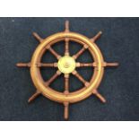 A mahogany ships wheel with ring-turned spindles and brass mounts, the central boss reading