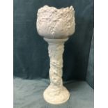 A white glazed jardinière on stand, the vine embossed column supporting a leaf moulded vase -