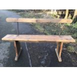 A Victorian pine bench with rounded back rail on iron supports above a plank seat, raised on