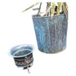 A tubular copper log bin with swing handles planted with a variegated cactus type shrub; and a