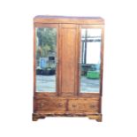 An Edwardian stained wardrobe with caddy shaped moulded top above two bevelled mirrored doors
