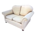 A contemporary upholstered sofa with loose cushions above a sprung seat flanked by padded scrolled