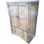 An oak cabinet with fluted pilasters framing panelled doors with press carved vine frieze and