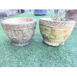 A pair of circular composition stone tapering garden pots with ropetwist rims above friezes with