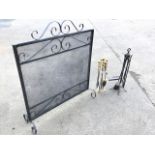 A rectangular wrought iron firescreen with scrolled decoration and mesh panel raised on scrolled