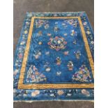A chinoiserie woven wool carpet with blue ground, the field with vases of flowers and central