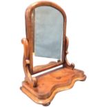 A Victorian mahogany dressing table mirror with arched cushion moulded frame to plate, on scrolled