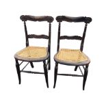 A pair of Victorian ebonised chairs with carved back rails on ring-turned supports above kidney