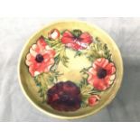 A circular Moorcroft tube line bowl decorated with poppies and leaves on pale green ground -