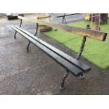 A long garden bench with twin plank seat and batten back, raised on three Victorian cast iron log