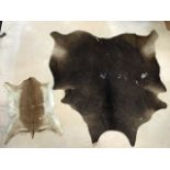 A large cowhide rug - 67in x 69in; and a smaller skin rug - 34in x 24in. (2)