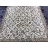 A Wilton style carpet woven with busy field of floral medallions and flower sprays on ivory