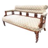A late Victorian walnut sofa with padded back and rounded arms on pierced vase shaped splats, the