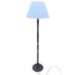A stained standard lamp with conical fabric shade on turned column, above circular moulded base. (