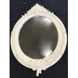 A large white painted Victorian style mirror with oval bevelled plate in leaf moulded frame, with