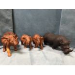 A carved African rhino with chip carved folded skin; and a later set of three carved hardwood