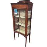 An Edwardian mahogany display cabinet with scrolled floral swagged decoration to upstand and frieze,