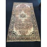 An oriental rug woven with central ivory scalloped floral medallion and spandrels on pink field with