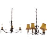 A painted wrought iron hanging light with four scrolled branches supporting candlelights, hung by