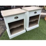 A pair of painted bedside cabinets with rectangular moulded tops above frieze drawers mounted with