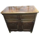 A nineteenth century French oak cupboard, the box top with cleated hinged cover above a pair of