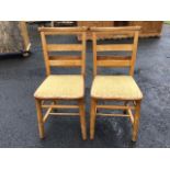 A pair of beech church chairs, the shaped ladder backs beneath buttoned rails mounted with hymn book