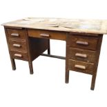 An oak kneehole desk, with rectangular rounded top above a central frieze drawer, framed by