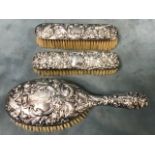 A Victorian ladies silver dressing table set embossed with birds, masks, and foliate scrolling -