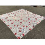 A Victorian patchwork quilt sewn with red arrow/heart style motifs on pink speckled ground, the back