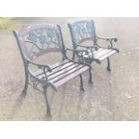 A pair of cast iron garden armchairs with arched backs framing pierced floral panels, having