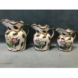 A set of three Victorian graduated jugs decorated with flowers framed by embossed copper lustre
